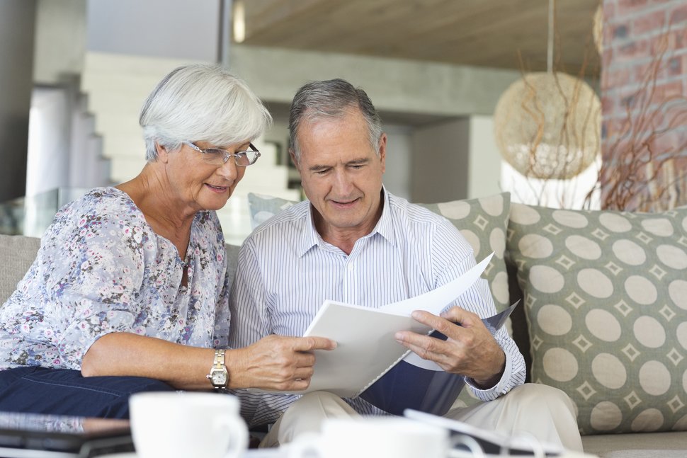 Older couple sitting on a couch looking at a report
